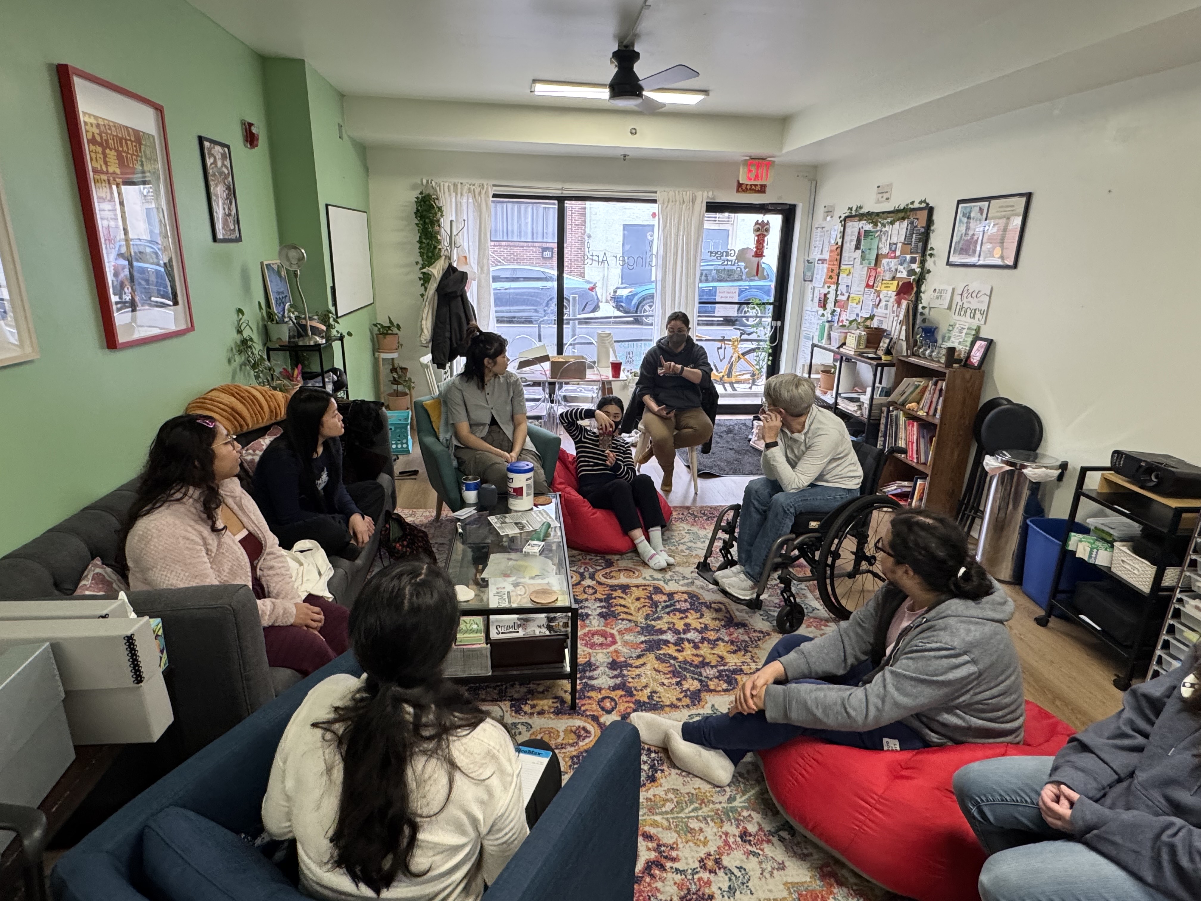Community members at Ginger Arts sit around a table talking